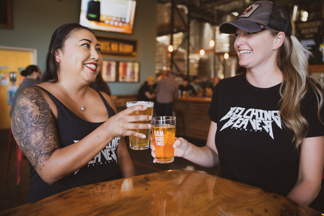 Picture of two females at Belching Beaver Oceanside with pint glasses 
