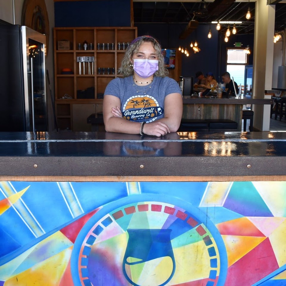 woman in mask in open window of groundswell brewery chula vista