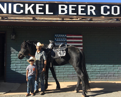 picture of two people with a horse in front of Nickel Beer Co. sign